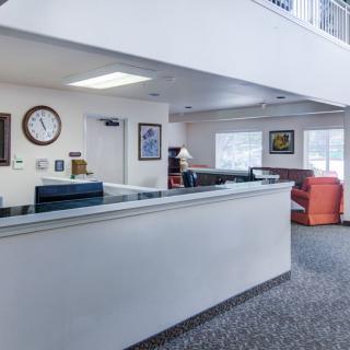 A clean and spacious lobby area featuring a reception desk, seating, and a wall clock.