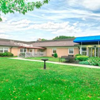 A serene view of a healthcare facility surrounded by green grass and clear skies.