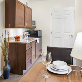 A cozy kitchen and dining area featuring wooden cabinets, a microwave, and a neatly set table with plates and glasses.