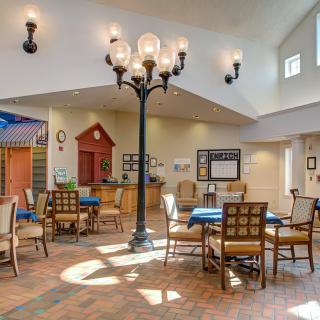 A well-lit dining area with tables and chairs arranged under elegant ceiling lights.