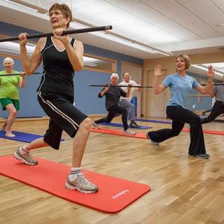 A group of seniors participating in an exercise class using fitness bars.