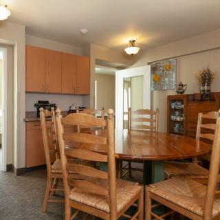 A cozy dining room with a wooden table and chairs, adjacent to a kitchen area.