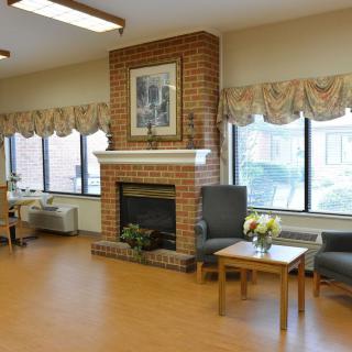 A cozy living room with a brick fireplace and large windows, featuring comfortable seating and tasteful decor.