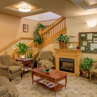 A cozy living room with a fireplace, seating area, and wooden staircase.