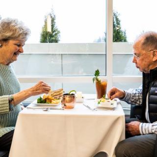 An elderly couple enjoys a meal together at a restaurant table.