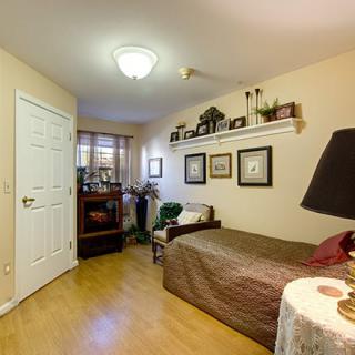 A cozy bedroom with a bed, wall shelves displaying decorations, and framed art.