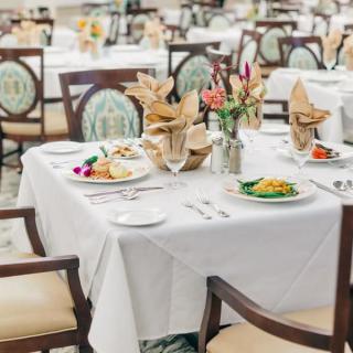 An elegantly set dining table in a restaurant, featuring neatly arranged napkins and a floral centerpiece.