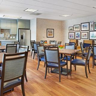 A modern dining area with multiple tables and chairs, featuring a kitchen space and decorated walls.