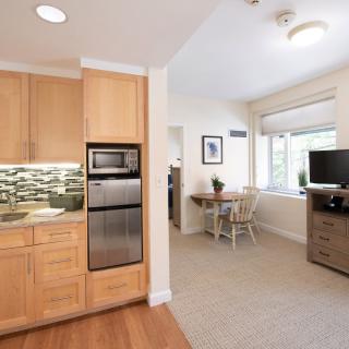 A modern, open-concept kitchen and living area featuring wood cabinetry and stainless steel appliances.