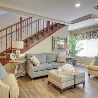 A cozy living room featuring a sofa set, armchairs, and wooden stairs.