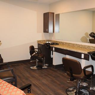 A modern hair salon interior with chairs, a large mirror, and a countertop.