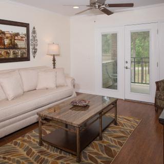 A cozy living room featuring a light-colored sofa, a stylish coffee table, and natural light streaming in through double doors.