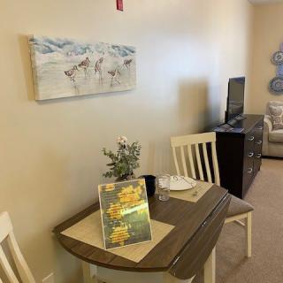 A cozy dining area with a small table set for two, adorned with flowers and artwork on the wall.