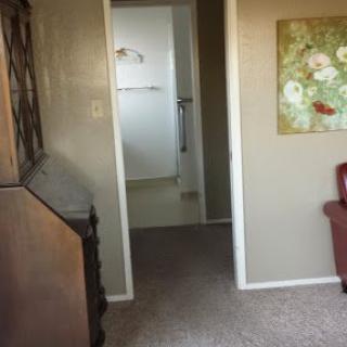A view of a room interior featuring a doorway leading to a bathroom, with furniture and a painting on the wall.