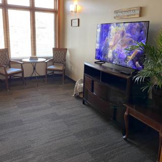 A cozy living room setup featuring a television and seating area with natural light.