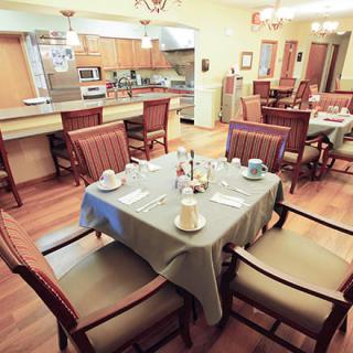 A cozy dining area connected to a modern kitchen, featuring a neatly set table with wooden chairs.