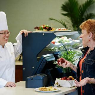 A chef and a customer having a conversation at a restaurant counter.