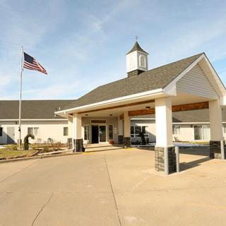 The image shows a building entrance with an American flag flying nearby.