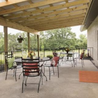 A cozy patio with outdoor seating and a pergola, offering a view of the garden.