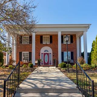 A classic colonial-style brick house with large columns and well-maintained landscaping.