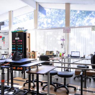 A spacious and well-lit classroom filled with modern furniture, including tables and chairs, providing an ideal workspace for learning.