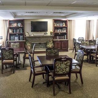 A cozy lounge area with tables and chairs, featuring bookshelves and a television.