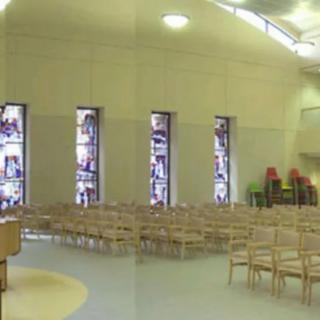 Interior of a church with seating and stained glass windows.