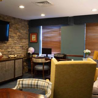 A cozy living room with a seating area, television, and desk by the window.