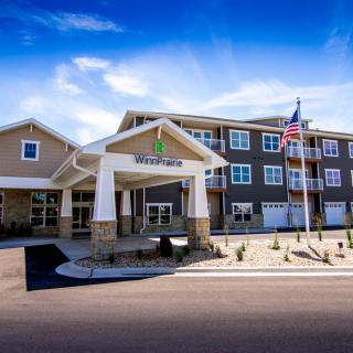 A modern hotel building with an entrance canopy, set under a clear blue sky.