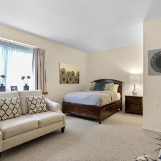 A cozy bedroom with a bed, sofa, and soft lighting creating a comfortable and inviting atmosphere.