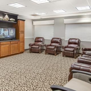 A cozy waiting room with leather recliners and a television.