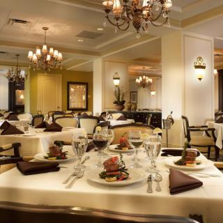 An elegant restaurant interior with beautifully set tables and chandeliers.