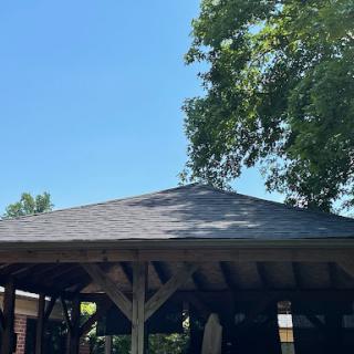 A beautiful gazebo under a clear blue sky, surrounded by lush greenery.