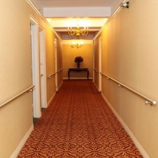 A hotel hallway with patterned carpet and soft overhead lighting.