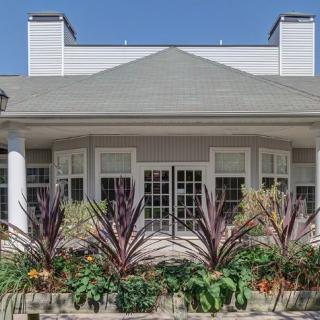 A house with a landscaped front yard featuring various plants and large windows.