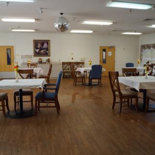 An empty dining room with neatly arranged tables and chairs on a wooden floor.