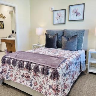 A cozy bedroom with a floral patterned bedspread, decorative pillows, and soft lighting from bedside lamps.