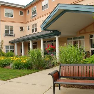 A welcoming building entrance with a landscaped garden and bench.