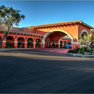 A Mediterranean-style hotel entrance with a landscaped driveway and arched portico.