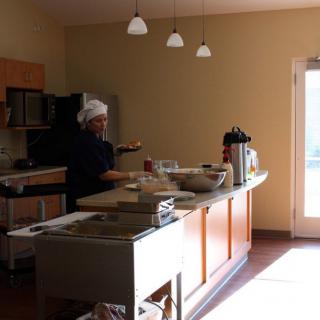 A chef working in a well-lit kitchen with various appliances and a countertop full of ingredients.