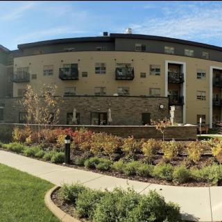 A modern apartment building with well-maintained landscaping and a paved pathway.