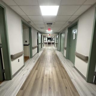 A view down a hospital hallway with doors leading to various rooms.