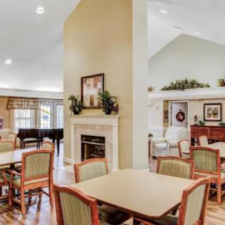 A well-decorated community dining area featuring tables, chairs, a fireplace, and a piano.