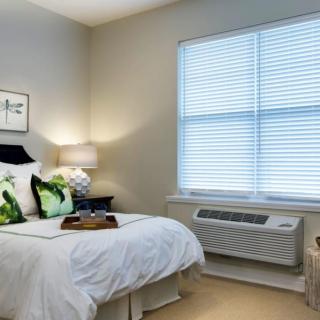 A cozy bedroom with a neatly made bed, decorative pillows, and a bedside lamp.