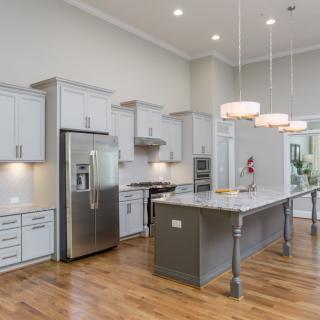 A modern kitchen with a large island, stainless steel appliances, and bright lighting.