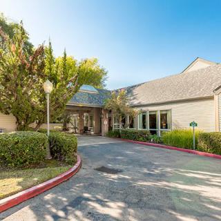 The entrance to a well-maintained building with surrounding trees and landscaping.