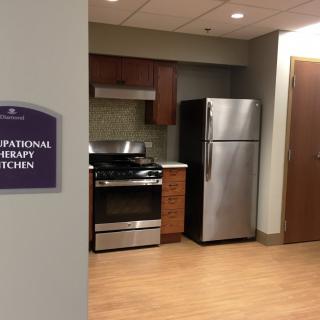 A modern therapy kitchen featuring a stove and refrigerator.