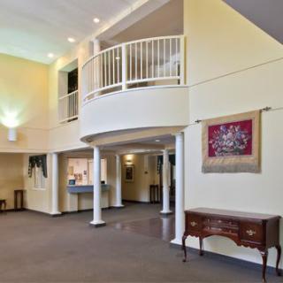 A spacious lobby area featuring a balcony, decorative columns, and classic furniture pieces.