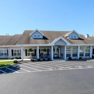 A commercial building with a spacious parking lot under a clear blue sky.