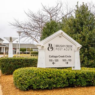 A sign in front of a residential building surrounded by greenery.